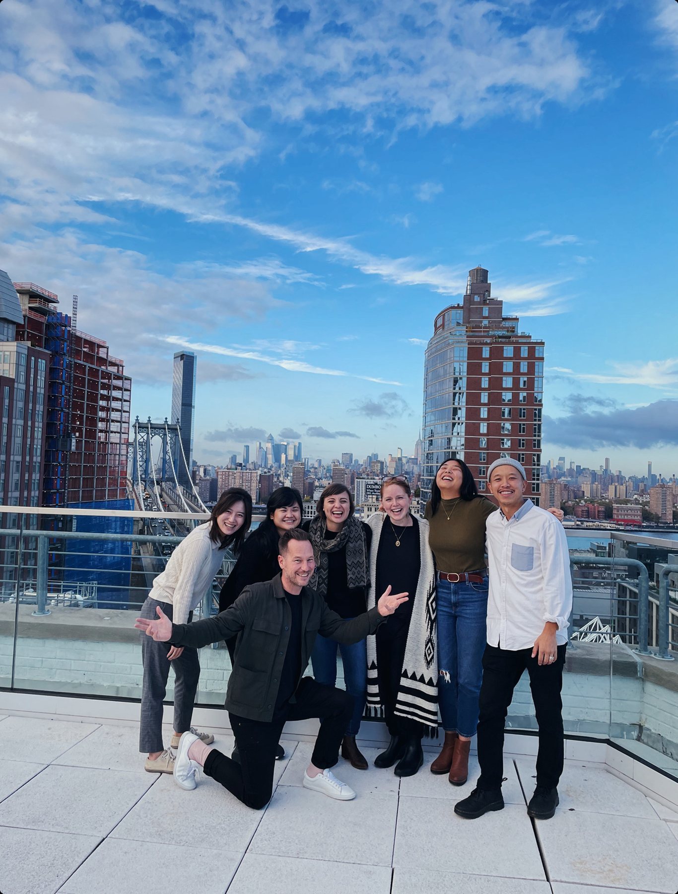 Team on a rooftop in Brooklyn with the Manhattan Bridge behind them